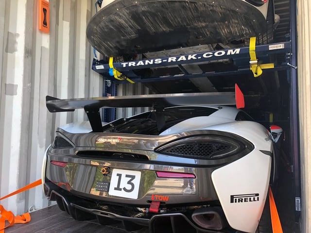A luxury sports car secured inside a metal shipping container using a precision-engineered steel racking system, illustrating safe and efficient containerised transport for high-value vehicles.