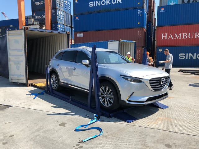 A modern electric vehicle secured inside a metal shipping container on a raised racking system, illustrating safe and efficient containerised EV transport using sustainable vehicle racking technology.