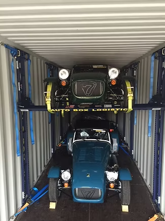 Two classic cars secured on a stacked loading system inside a shipping container for international car transport and logistics shipping.