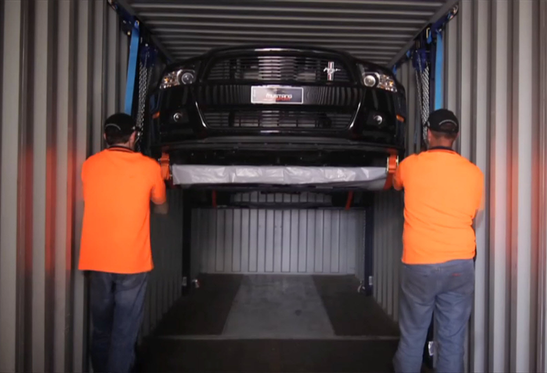 Car being securely transported using a containerised shipping solution.